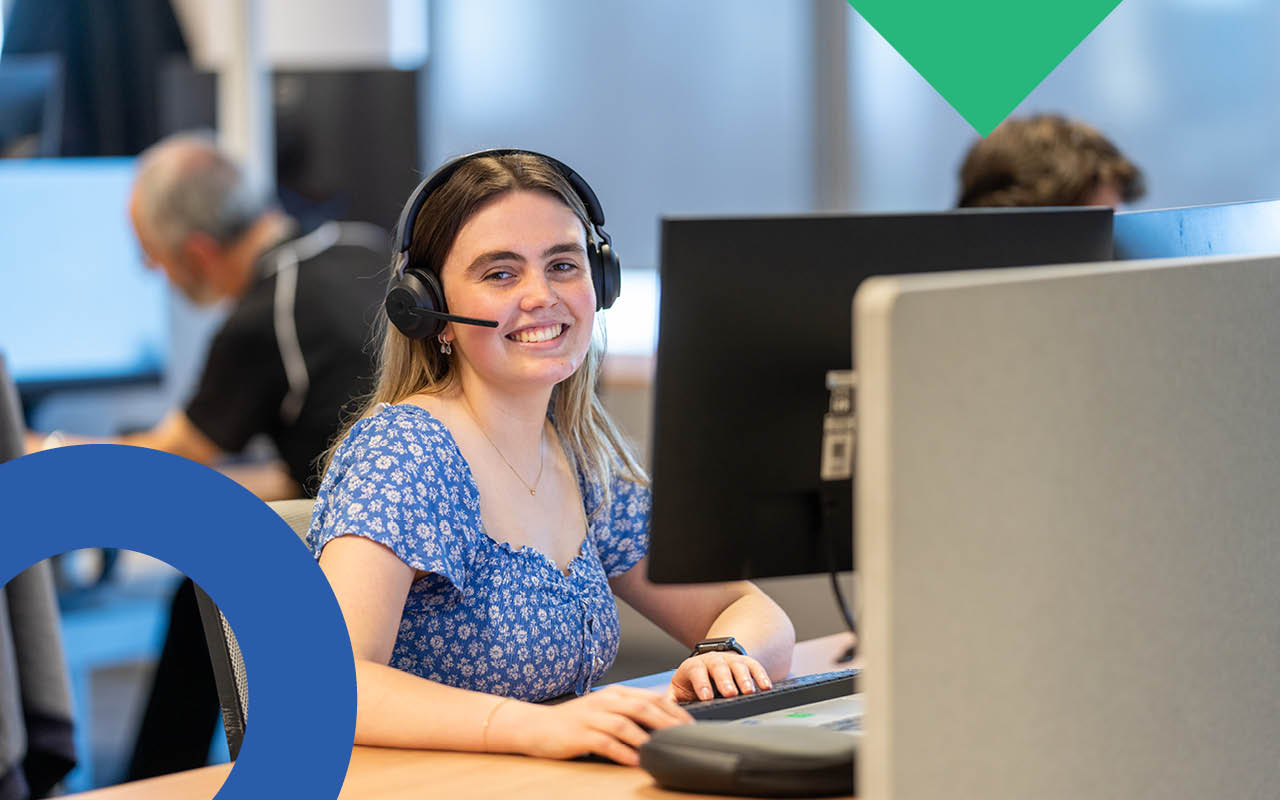 A smiling woman sitting at a computer desk
