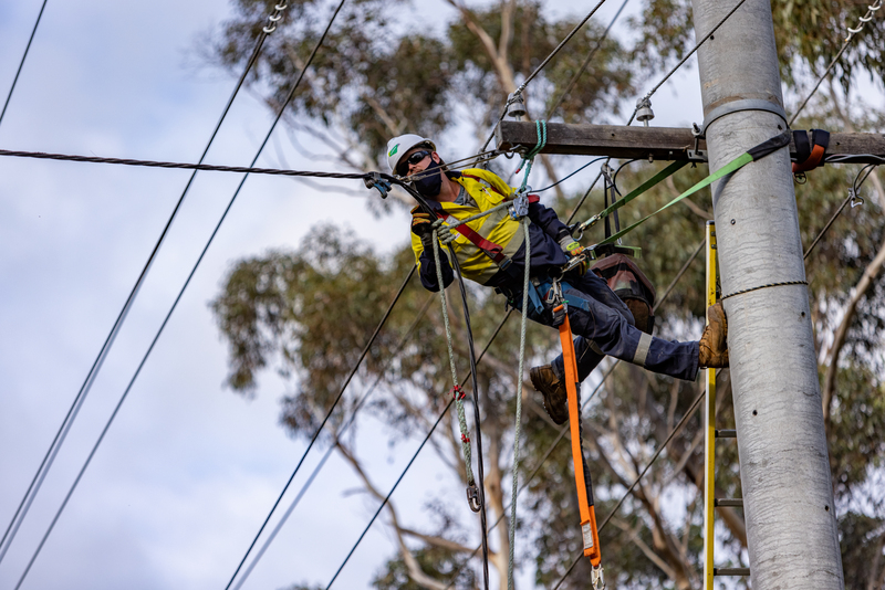 A man wearing high-vis repelling from a powerline