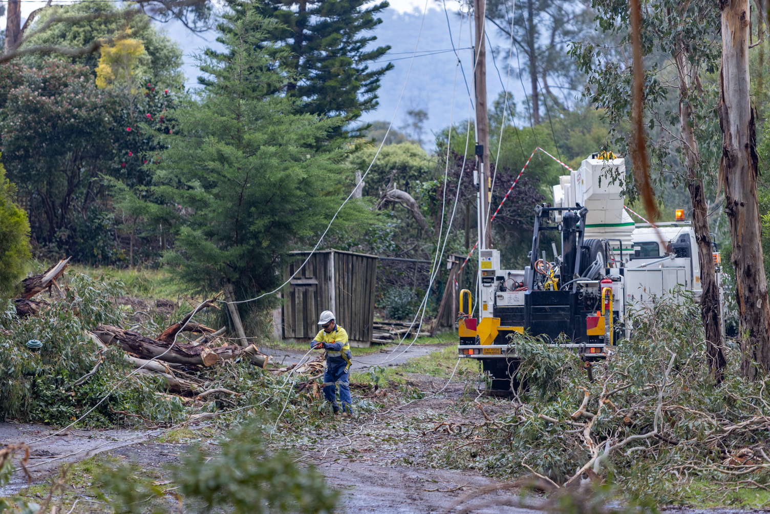 A man outside repairing damaged powerlines after a storm
