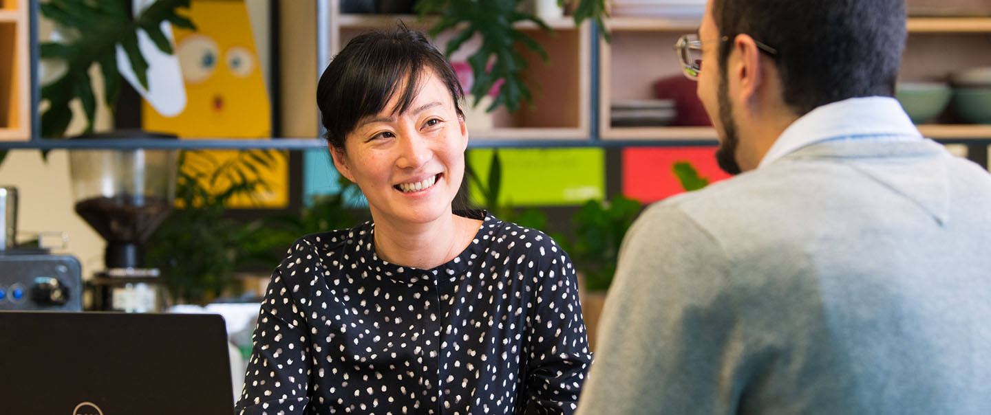 A woman with a laptop smiling at a man