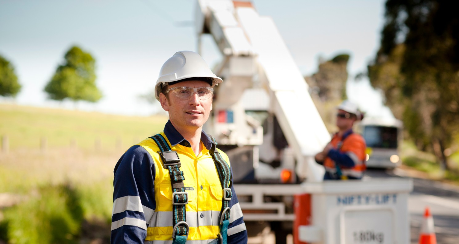 A man in high vis stands outside infront of heavy machinery