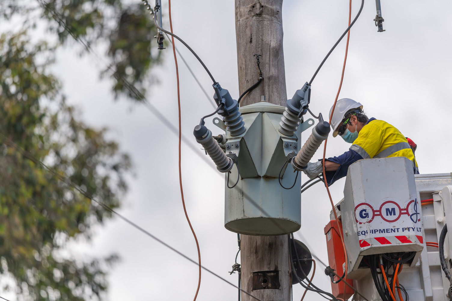 A person outside in high vis working on a powerline