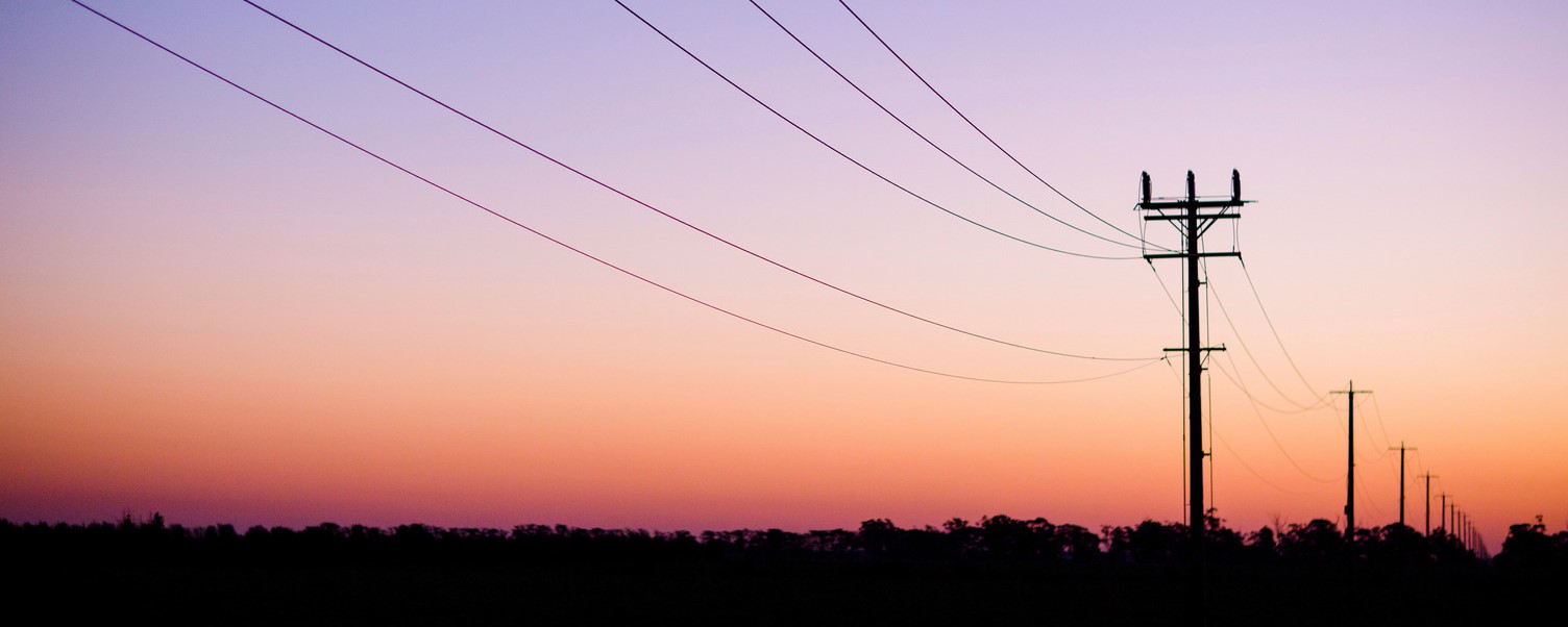 Electricity powerlines spanning across at road at dawn