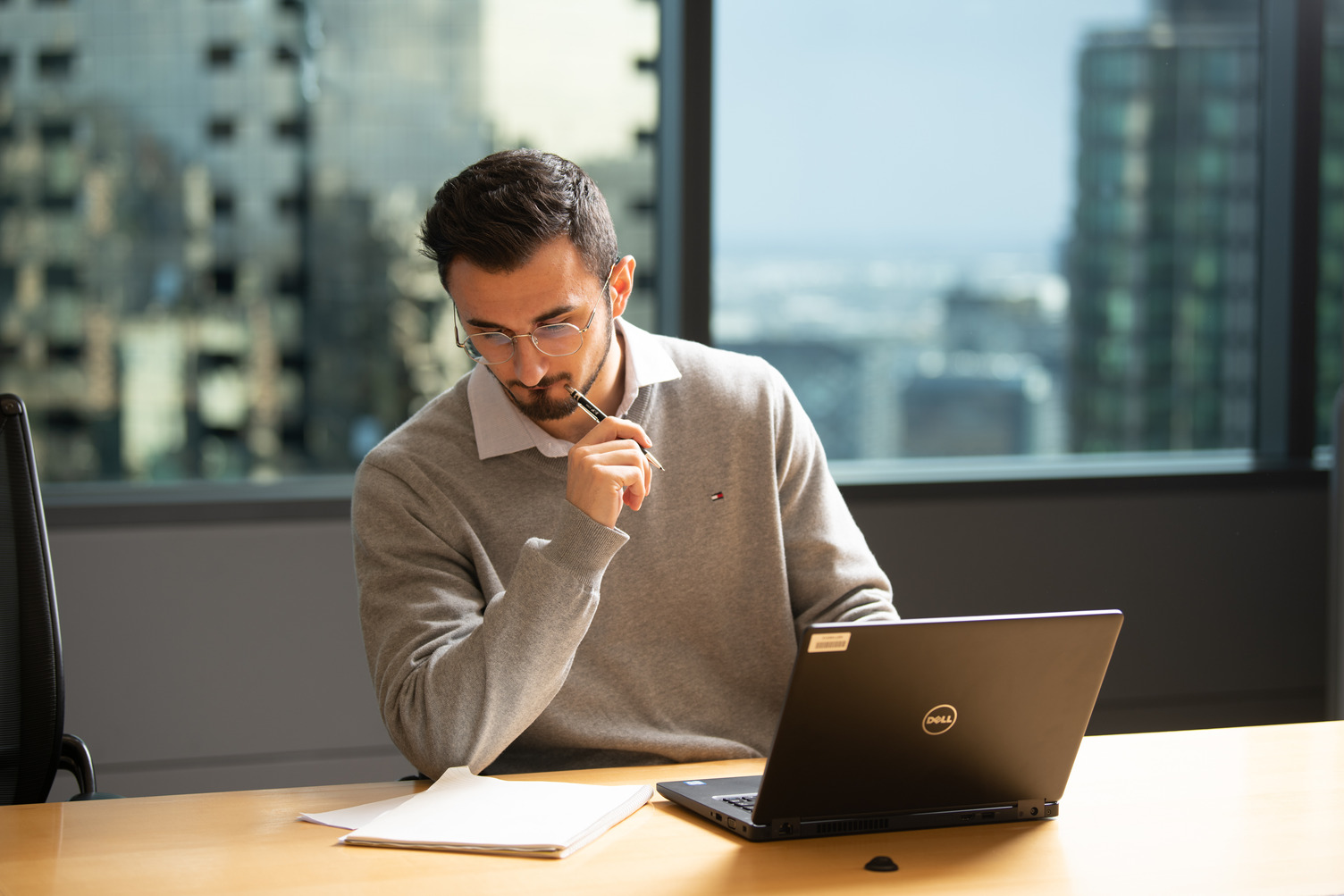 A person thinking while looking at documents next to a laptop